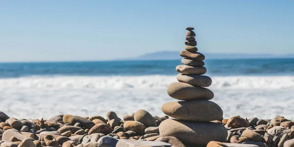 A banner image showing a stack of rocks against an ocean background. Photo by Jeremy Thomas on Unsplash.